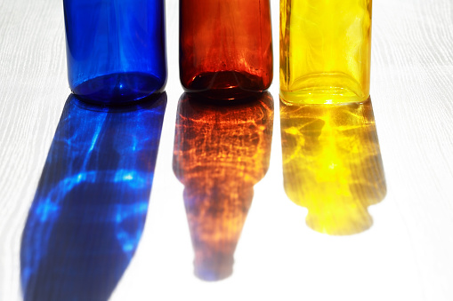 Set of empty multicolored glass bottles with nice shadow against sun light