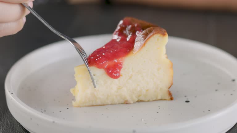 Boy hands cutting strawberry sauce over cheese cake