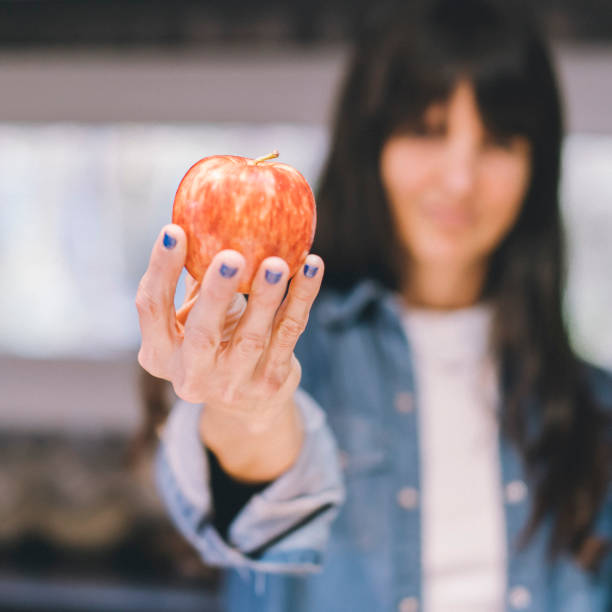 istock Woman showing an apple in her kitchen 1758025841