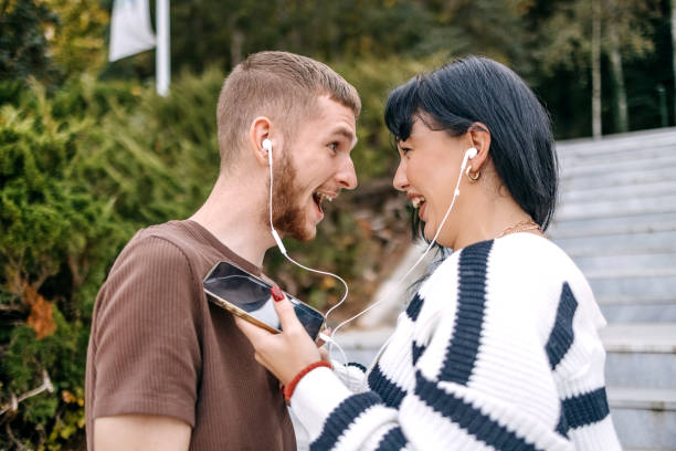 casal da geração millennial passando um tempo ao ar livre no outono ouvindo música juntos usando o telefone celular - heterosexual couple audio - fotografias e filmes do acervo