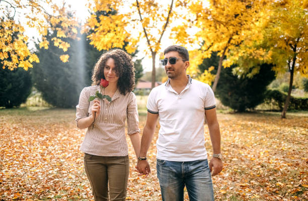 Couple in love walking in city park and having fun on yellow leaves in Autumn