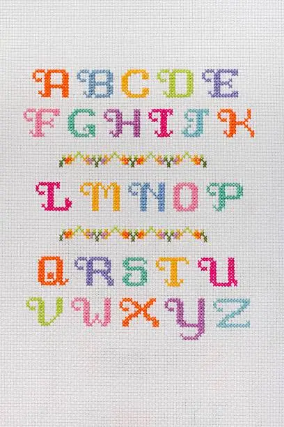 Alphabet embroidered with colored thread on canvas