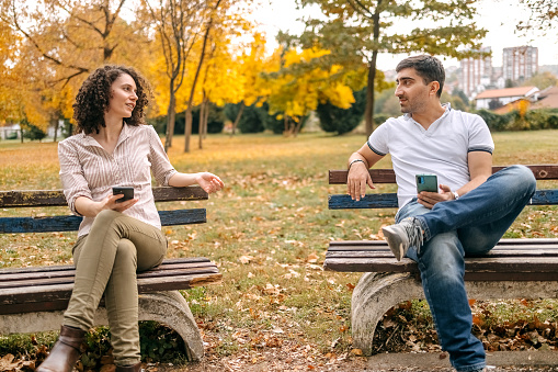 Couple sitting in city park and getting to know each other better in Autumn