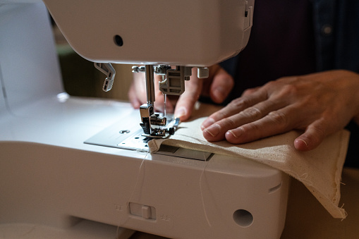 Close up woman working with sewing modern machine