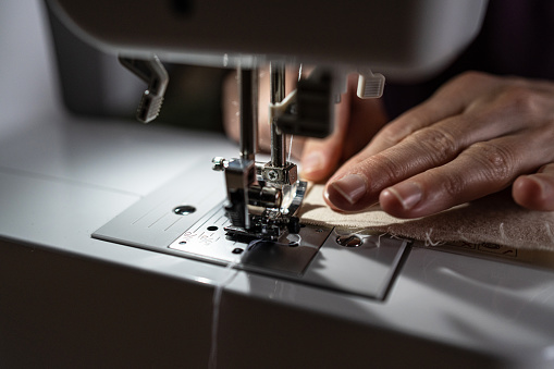 Close up woman working with sewing modern machine