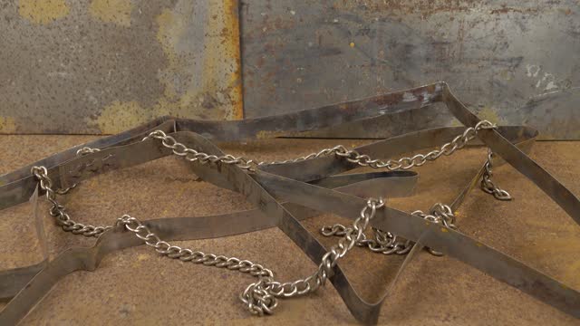 A roll of metal tape and a chain lie on a rusty sheet of metal