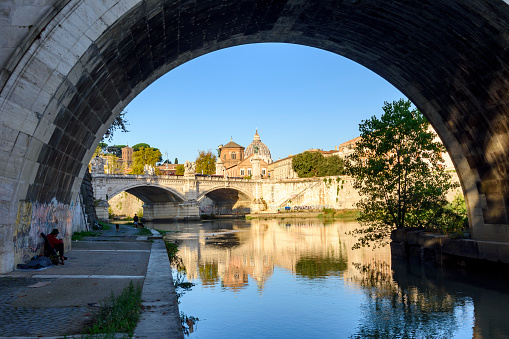 Rome, Italy - 04 October 2022: St. Angel bridge over Tiber river with St Peter's basilica in Vatican at background