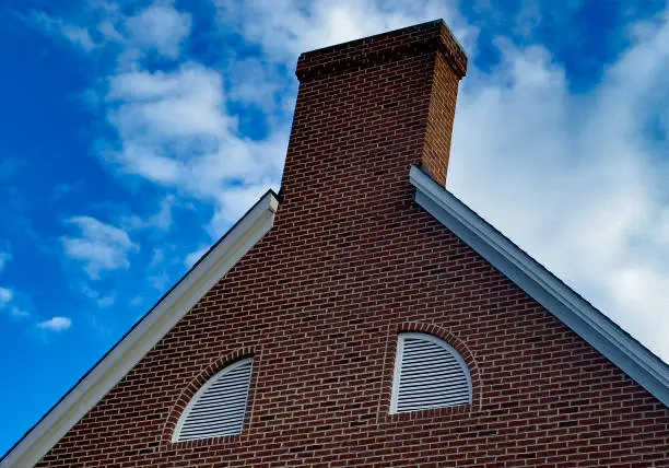 Photo of Colonial style btick chimney in a pleasant blue sky