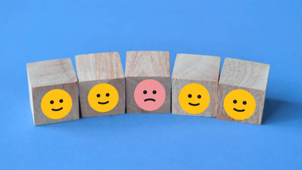 istock Sad face among happy faces, icon on wooden block cube 1758084251