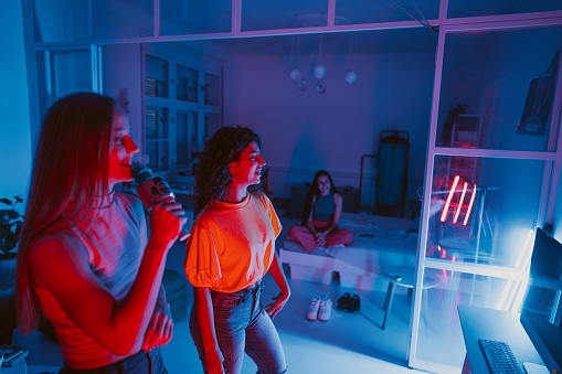 Photo of a couple of girls having a house party with a karaoke theme