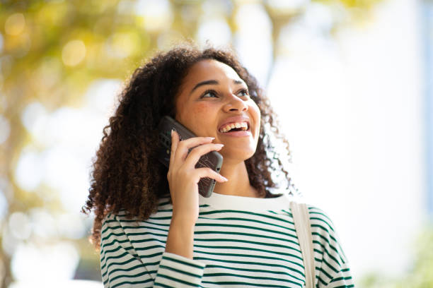 istock smiling young woman talking with cellphone and looking up 1758099179