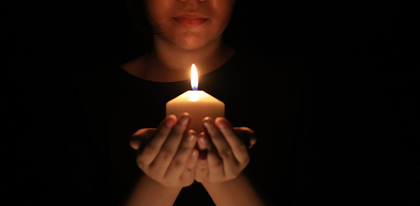 Burning candle in front of a black background with place for text. Close up.