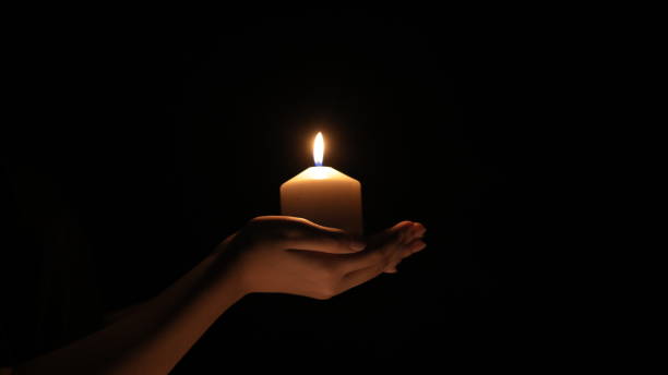 istock Female hands holding burning candle on black background 1758104402