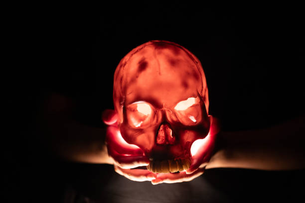 Hands holding an illuminated  skull in a sombrero on a dark background