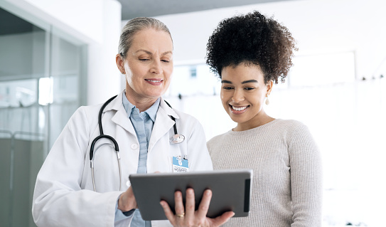 Doctor, woman and tablet in healthcare consultation, hospital support and feedback or online results. Medical professional and happy patient for digital x ray, charts or technology with clinic advice