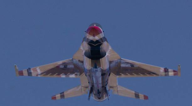 Mathers, United States – May 14, 2023: A military fighter jet soaring through the sky with its wings spread in a V-shape, the sky a brilliant blue background