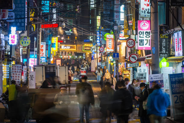 Seoul neon nights busy downtown shopping streets South Korea People walking through the neon lit night streets of Sinchon in the heart of Seoul, South Korea’s vibrant capital city. kangnamgu stock pictures, royalty-free photos & images