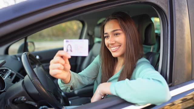 Young brunette woman showing her new drivers license