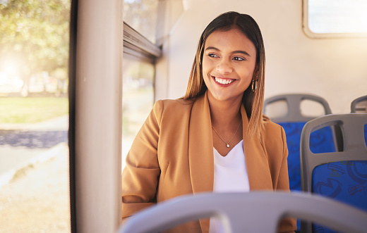Young, woman and commute to work by bus, public transportation and city with traffic. Employee, alone and smile in happiness on face for career, occupation and traveling with service, metro or auto