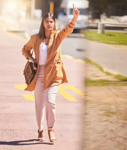 Woman, walking and wave to taxi in city for bus, cab or commute transportation and travel in cbd for business. Person, hand and sign to call attention of taxicab driver, service or passenger in town