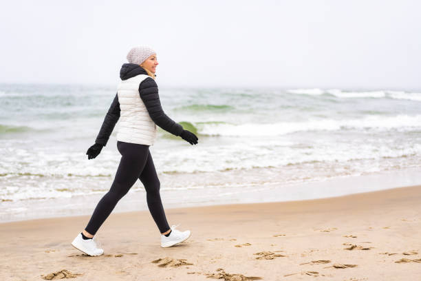 istock Mid adult woman walking on beach 1758149200