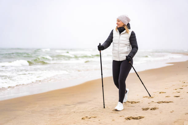 ビーチでノルディックウォーキングをする中成人女性 - nordic walking walking relaxation exercise women ストックフォトと画像