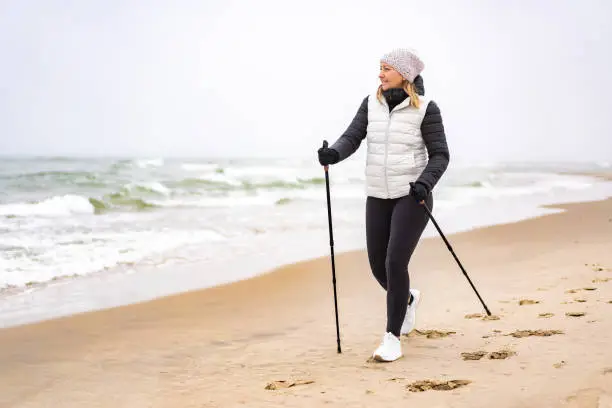 Mid adult woman exercising Nordic walking on beach