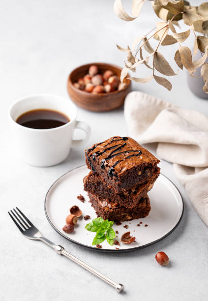 istock A stack of chocolate brownies with mint, hazelnuts and salted caramel on a white plate on a light background with cup of coffee and bowl with nuts. 1758162475