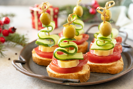 Creative appetizers christmas. Christmas tree canapes of salami, cheese, olives, tomatoes and cucumbers on a baguette.