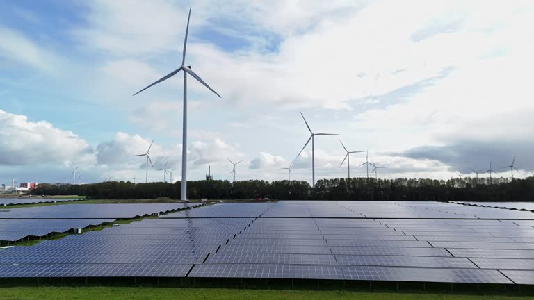 Solar panel park near city Delfzijl in the Netherlands with wind turbines in the background