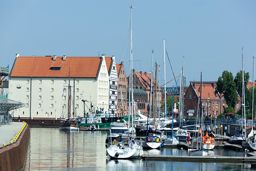 The view of a little marina in a canal and Gdansk old town buildings in a background (Poland).