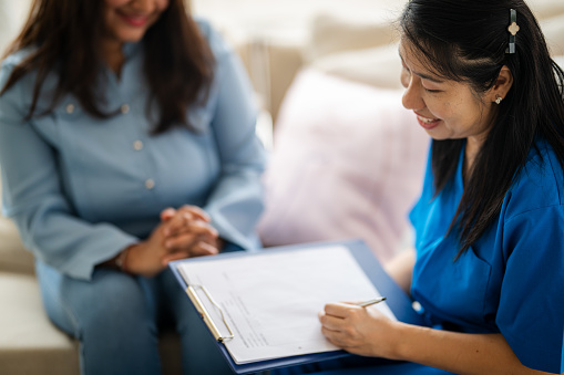 Closed up an Asian psychiatrist or professional psychologist conducts counseling or therapy sessions with female patients suffering from mental health problems.