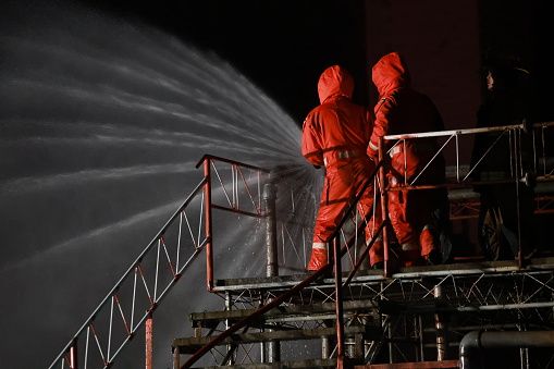 Fireman with red safety uniform. firemen use high-pressure water to extinguish a fire-closing valve gas jet