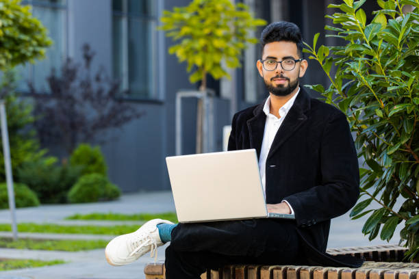 istock Happy Indian businessman typing working remote on wireless laptop computer browsing online outdoors 1758253517