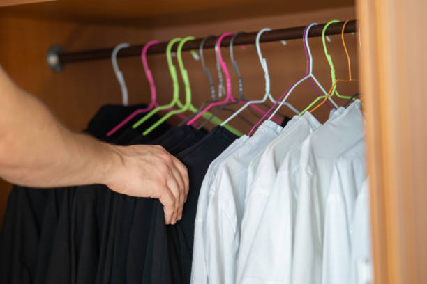 istock Young man choosing between black and white shirts in his wardrobe, black and white clothes only, guy holding black and white shirts hanging in his wardrobe 1758282540