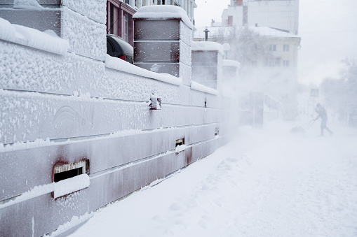 Blizzard on the streets of the city. A strong wind with snow blows passers-by off their feet. Frozen walls. Frost on the wall of the house. High quality photo