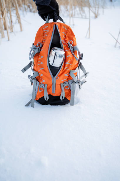 istock Backpack close-up. Camping equipment. Pack up for a winter hike. Take a thermos in your bag. Winter trip. 1758291667