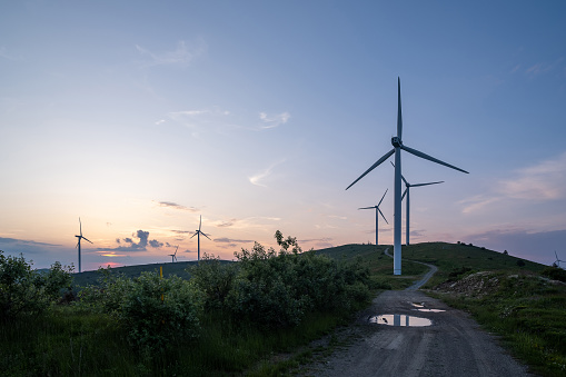 A group of wind turbines on a mountain ridge at sunset.