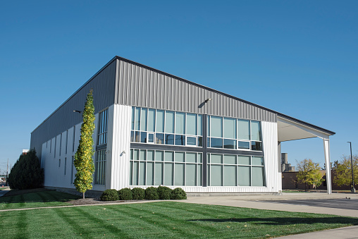 Modern building in gray and white aluminum siding and flat angled roofline and front windows.