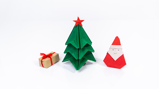 Original origami Christmas holiday card. Christmas tree, gift box and Santa Claus folded from paper. White background. Copy space.