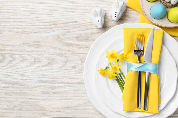 istock Festive table setting with painted eggs and cutlery on white wooden background, flat lay with space for text. Easter celebration 1758342183