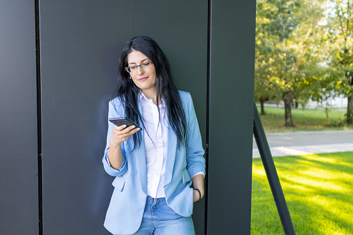 Portrait of beautiful and confident young business woman using smartphone during break time.