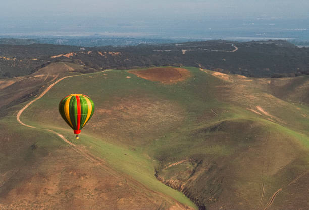 Green hot air balloon flying over city buildings