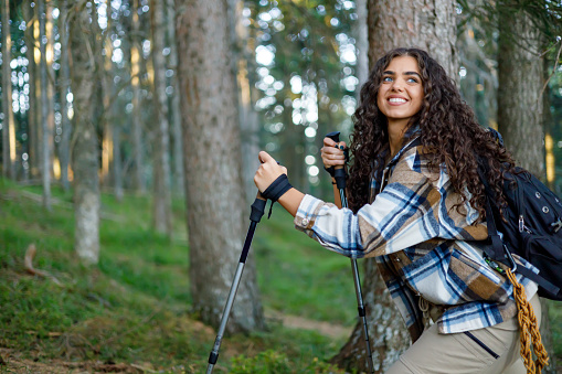 A young woman takes advantage of hiking sticks to maintain her balance while walking on a mountain path