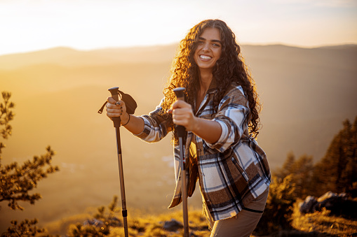 A young woman is seen making practical use of her trekking poles to successfully navigate her way through a mountain hike