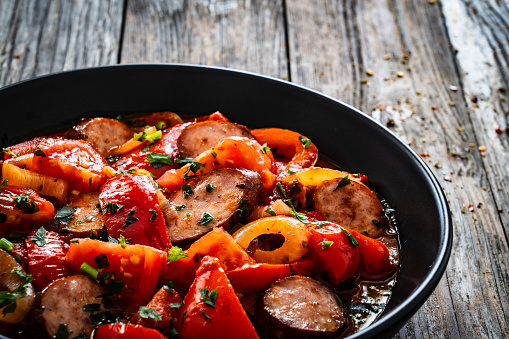 Delicious letcho - vegetables with sausages on wooden table