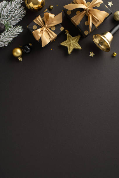 Deluxe Noel blessings inspiration. Overhead vertical view of opulent present boxes, extravagant tree decorations, confetti, ringing bell, frost-covered fir branch on background with space for greeting