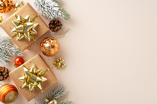 Seasonal Splendor: Overhead shot of festive gift boxes, opulent gold and orange ornaments, pinecones, and frost-kissed fir branches against a pastel beige surface, awaiting your personal touch