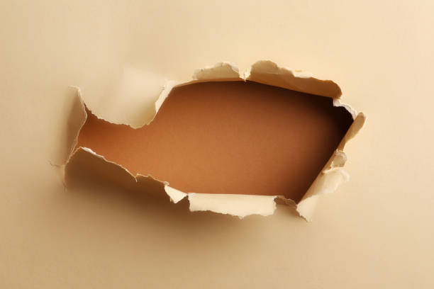 istock Hole in light beige paper on brown background 1758410755