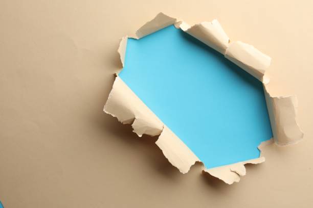 istock Hole in beige paper on light blue background, space for text 1758411328